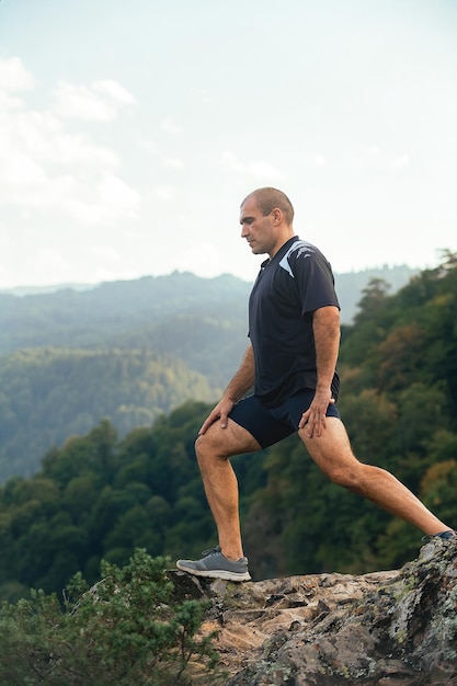 homme sportif faisant des étirements et de l'exercice sur la pente d'une haute montagne