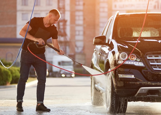 Homme sportif lavant sa voiture noire à l'extérieur