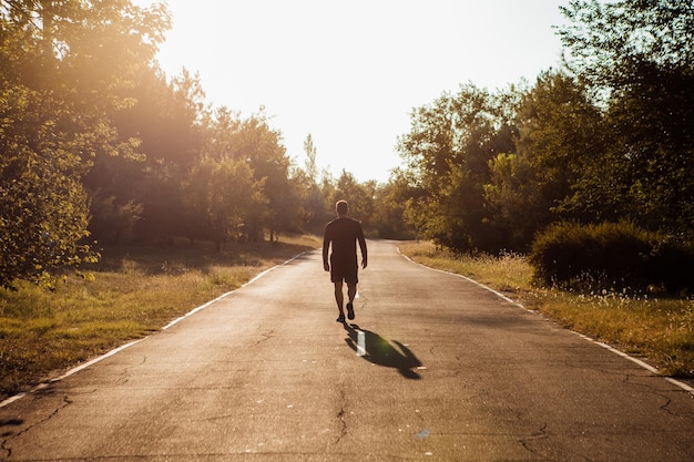 Homme sportif marchant dans la rue jeune et en forme homme ayant séance d'entraînement en soirée parc extérieur fond de coucher de soleil...