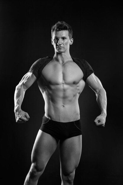 Homme sportif montre un corps musclé sur fond sombre