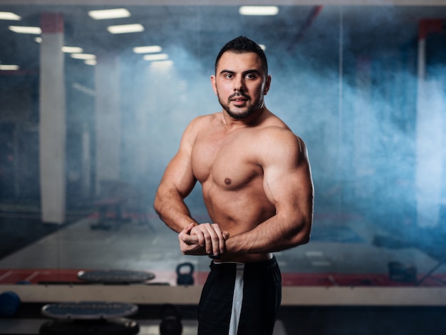 Homme sportif posant, exhibant ses muscles dans le gymnase