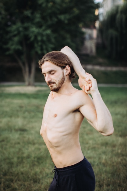 Homme sportif pratiquant le yoga en plein air