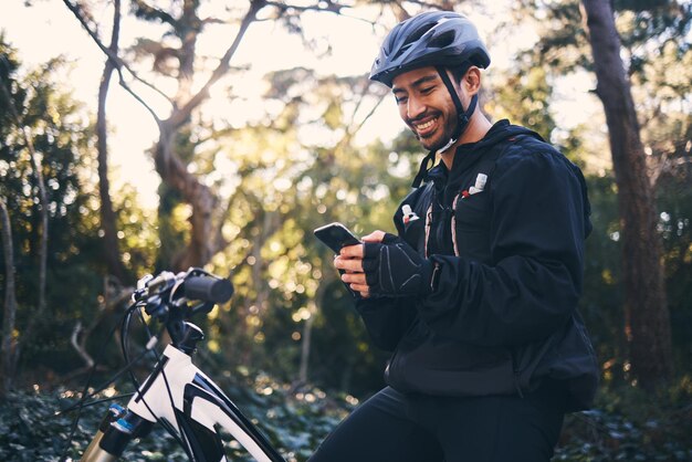 Homme sportif et téléphone en plein air pour le vélo de montagne ou l'entraînement et le sourire dans la nature