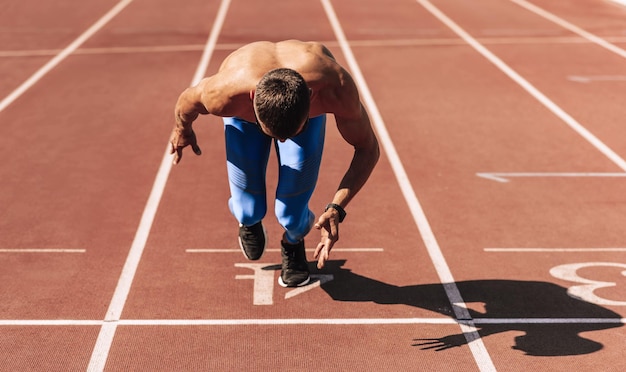 Homme sprinter se préparant à courir sur l'hippodrome du stade Sportif coureur masculin sprintant pendant la séance d'entraînement pour la compétition Sport et mode de vie sain