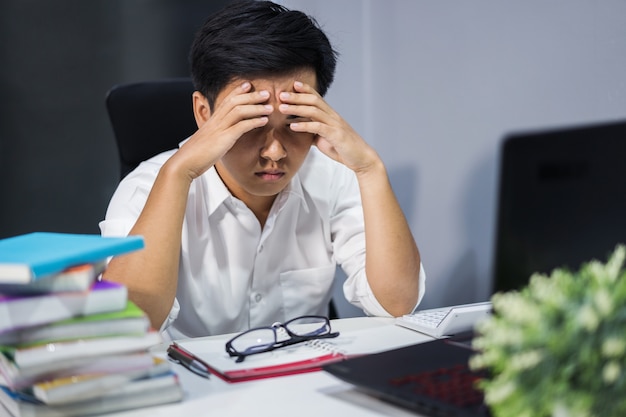 homme stressé étudiant avec livre et ordinateur portable