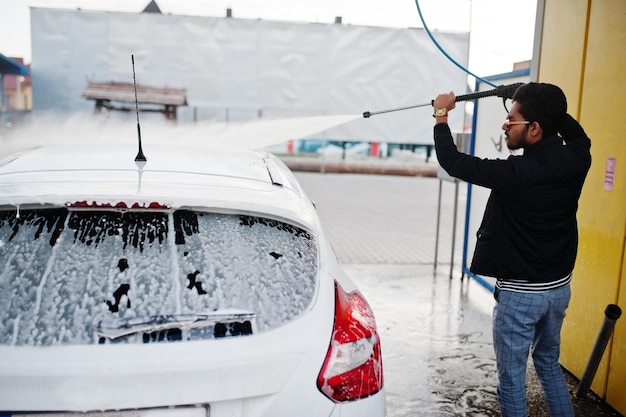 Homme sud-asiatique ou homme indien lavant son transport blanc sur le lave-auto.