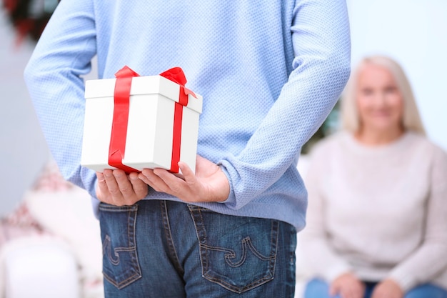 Homme supérieur cachant le cadeau de Noël pour sa femme à la maison