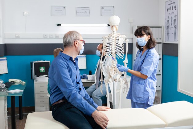 Homme supérieur regardant le squelette humain pour les soins chiropratiques