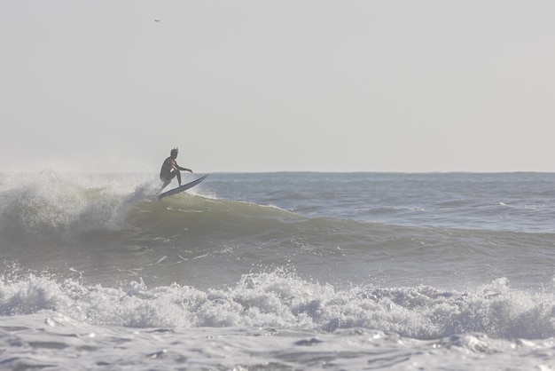 Un homme surfe sur les vagues en plein jour