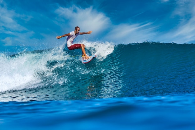 Homme surfer sur une vague bleue à la journée ensoleillée