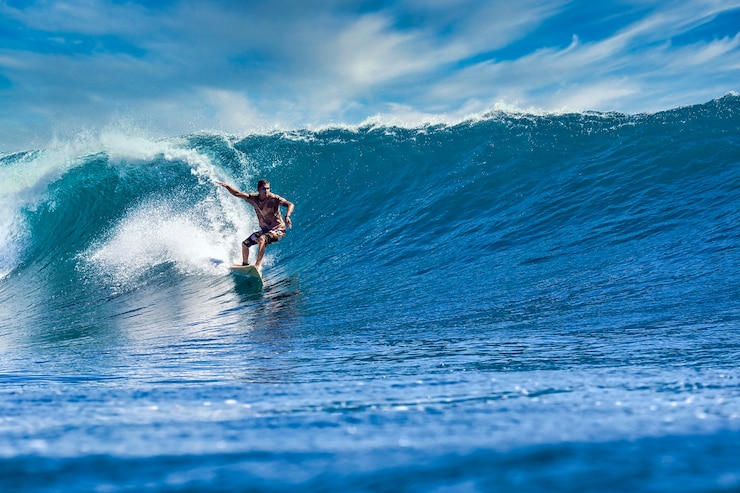 Photo homme surfer sur une vague bleue à la journée ensoleillée