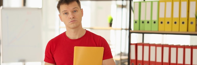 Homme surpris avec des documents en mains au bureau avec des étagères et des dossiers pour papiers