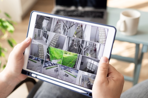 homme surveillant les caméras de vidéosurveillance modernes sur le système de sécurité de surveillance à l'intérieur d'une tablette numérique