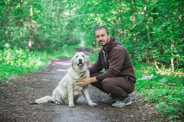 homme en survêtement promène un chien dans la forêt