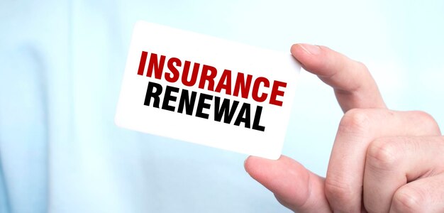 Un homme en sweat-shirt bleu tenant une carte avec le texte INSURANCE RENEWAL concept d'entreprise