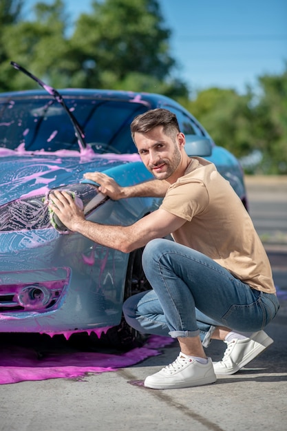 Photo homme sympathique essuyant la surface de la voiture