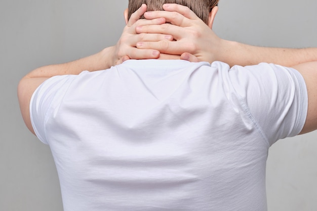 Un homme en T-shirt blanc lui masse le cou en raison de douleurs à la colonne vertébrale.