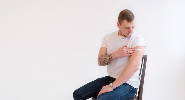 homme en t-shirt blanc souriant après avoir reçu la vaccination sur fond blanc.