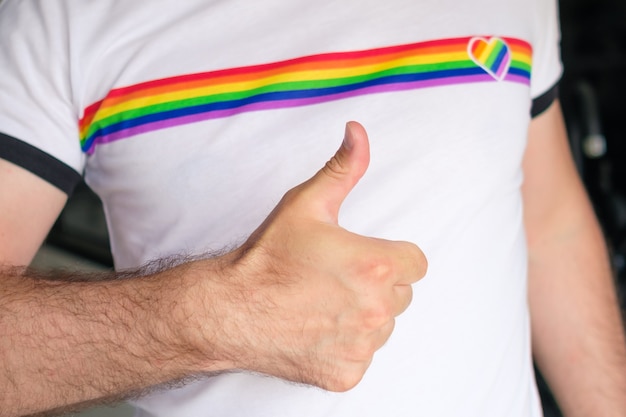 L'homme en t-shirt avec le drapeau lgbt montre un signe comme le concept des droits des homosexuels et des lesbiennes