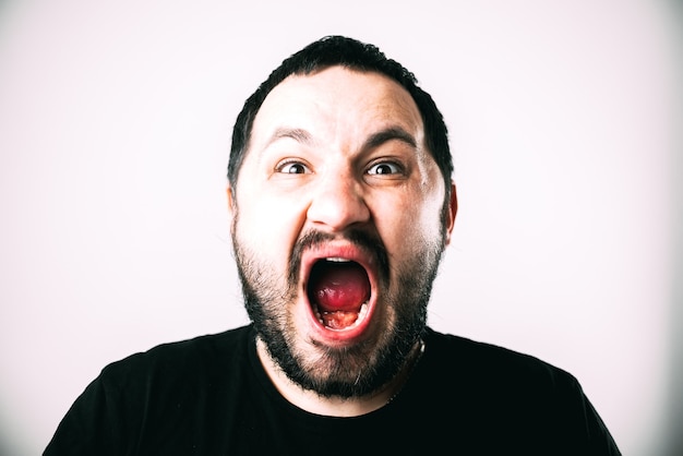 Un homme en t-shirt noir avec une barbe criant fort