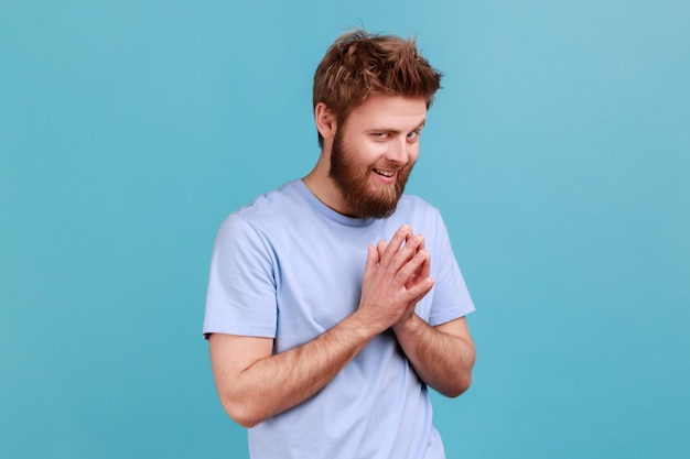 L'homme en T-shirt planifie quelque chose qui garde les mains ensemble fait des plans l'expression sournoise a l'air pensive