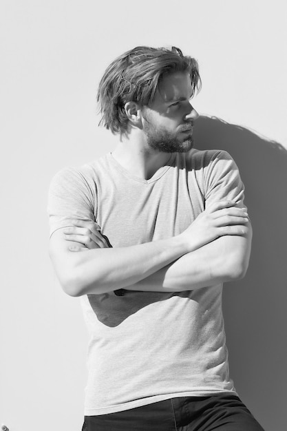 Homme en t-shirt pose avec les mains jointes sur le mur gris