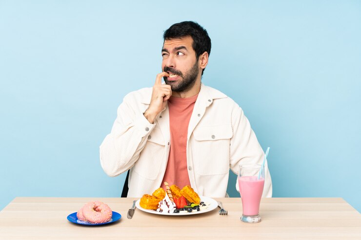 Photo homme, table, avoir, petit déjeuner, gaufres, milkshake, nerveux, effrayé