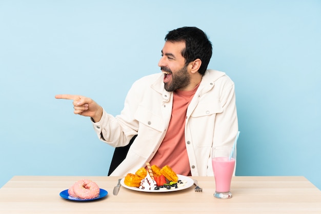 Homme, table, avoir, petit déjeuner, gaufres, Milkshake, pointage, doigt, côté, présentation, produit