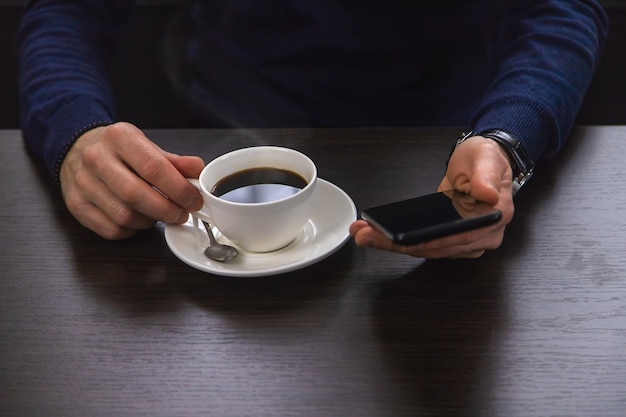 Un homme à une table avec un téléphone et une tasse de café