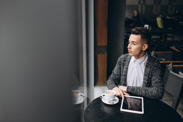 Homme avec tablette et café dans un café