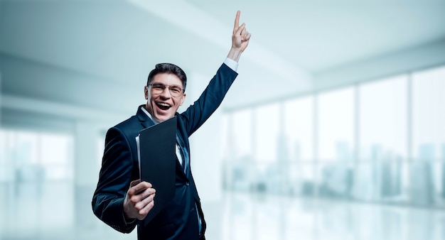 L'homme avec une tablette à la main hurle de joie au bureau. Le concept de la réussite en affaires.