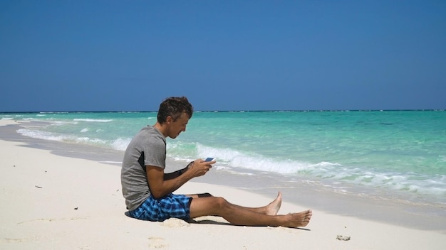 Homme avec la tablette sur la plage