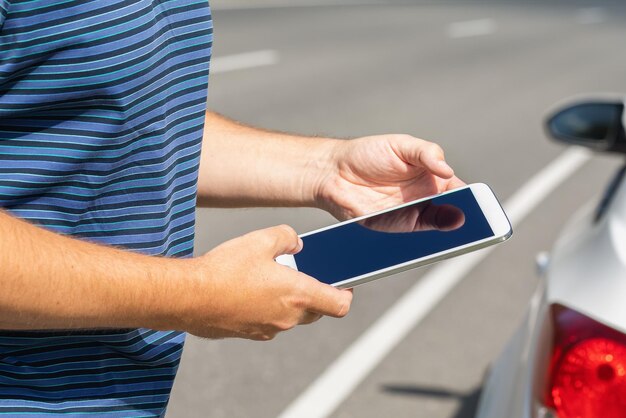 Photo un homme avec une tablette sur la route près de la voiture trouvant un éventuel dysfonctionnement sur la route