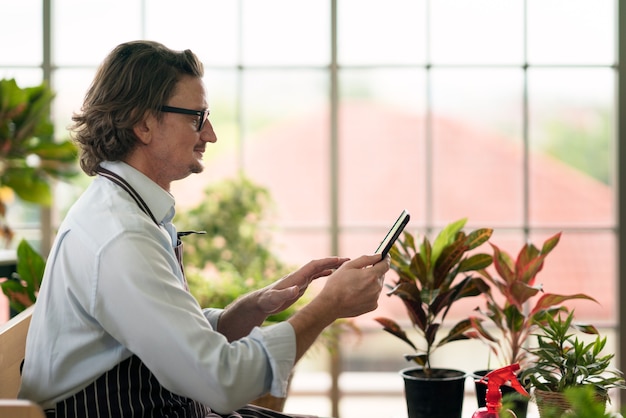 homme avec tablier en serre avec tablette