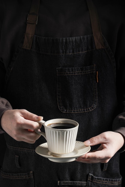 Un homme en tablier tient une tasse de café Détente avec café