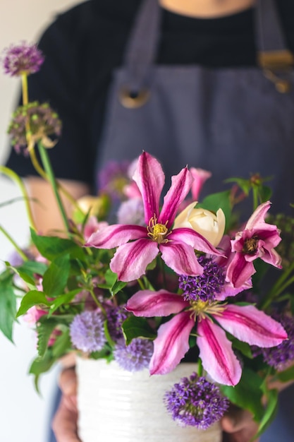 Un homme en tablier tient un vase de fleurs en gros plan