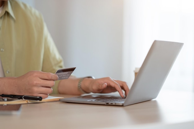 Photo un homme tapant son numéro de carte de crédit sur un site web commercial via son ordinateur portable alors qu'il était assis à une table