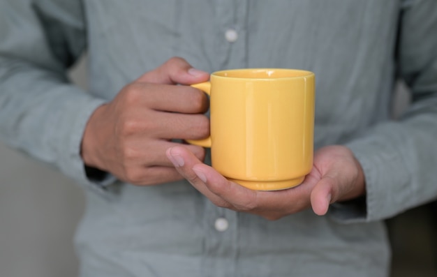 homme avec une tasse de café jaune à la main