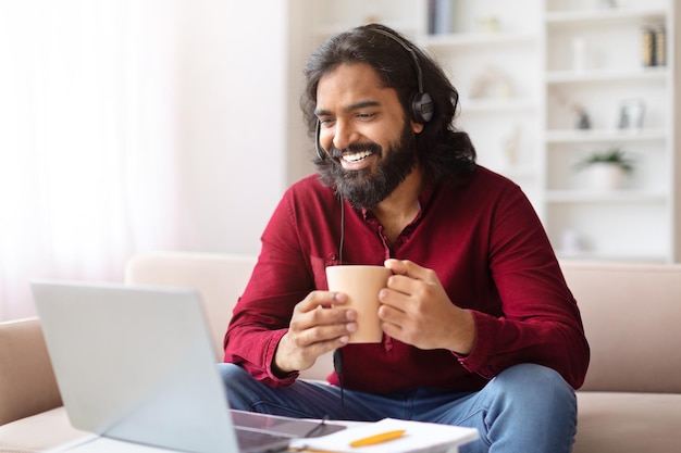 Un homme avec une tasse qui aime travailler sur un ordinateur portable