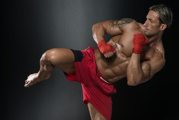 Un homme avec un tatouage dans des gants de boxe rouges Boxe sur fond noir Le concept d'un mode de vie sain L'idée du film sur la boxe