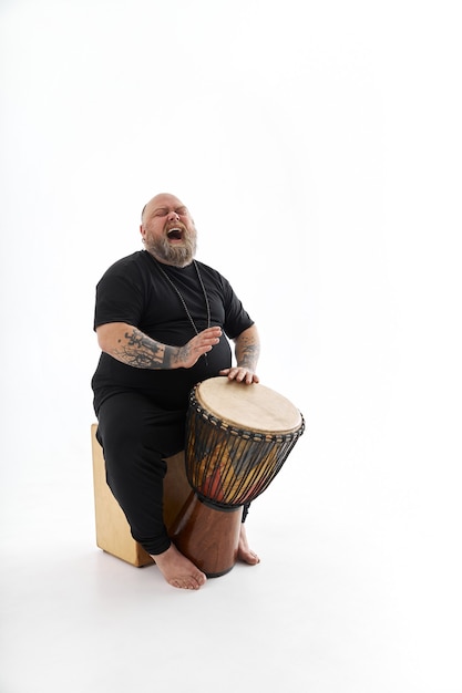 Homme tatoué barbu pose sur fond blanc