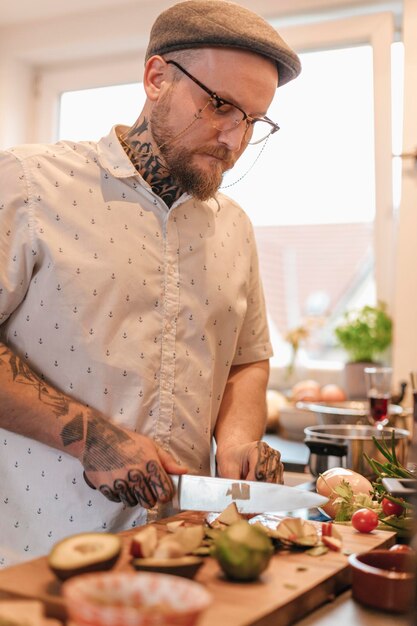 Homme tatoué préparant la nourriture dans la cuisine