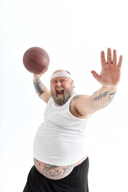 Homme tatoué en surpoids barbu avec ballon de basket en fond blanc