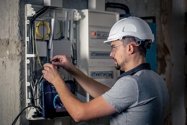 L'homme un technicien électricien travaillant dans un standard avec des fusibles utilise une tablette