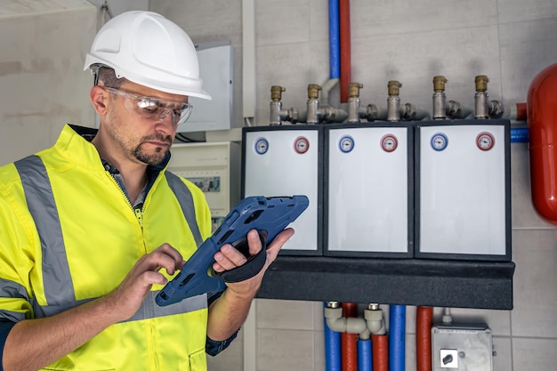 Photo l'homme un technicien électricien travaillant dans un standard avec des fusibles utilise une tablette