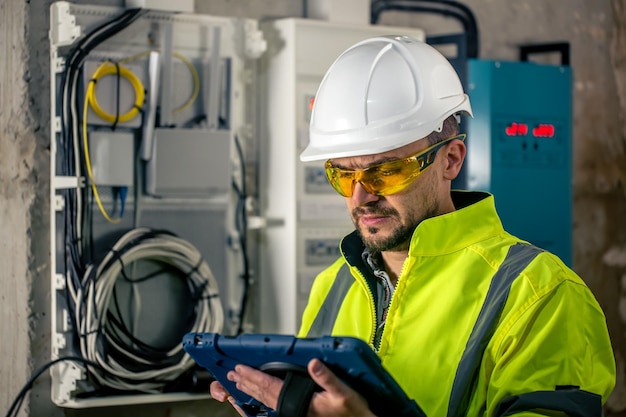 L'homme un technicien électricien travaillant dans un standard avec des fusibles utilise une tablette