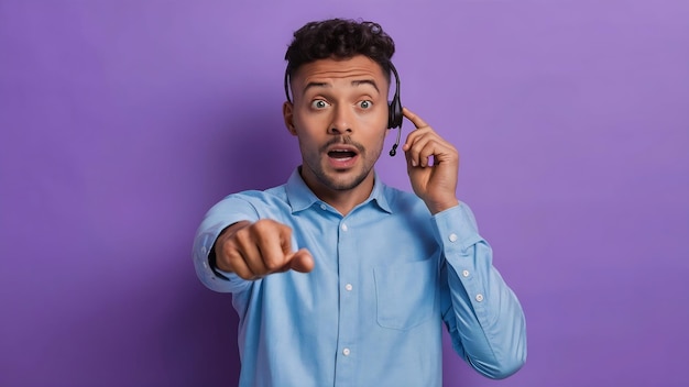 Photo homme de télécommercialisation travaillant avec un casque isolé sur fond violet surpris et pointant vers l'avant
