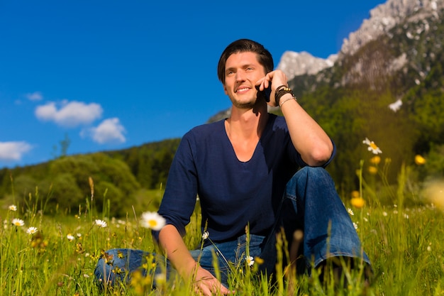 homme avec téléphone assis dans les montagnes