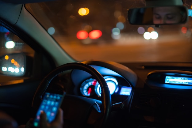 L'homme téléphone dans la voiture. Le soir la nuit