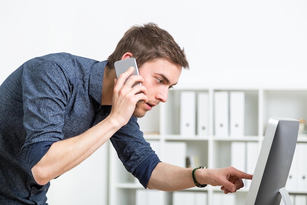 Photo homme avec téléphone et écran d'ordinateur